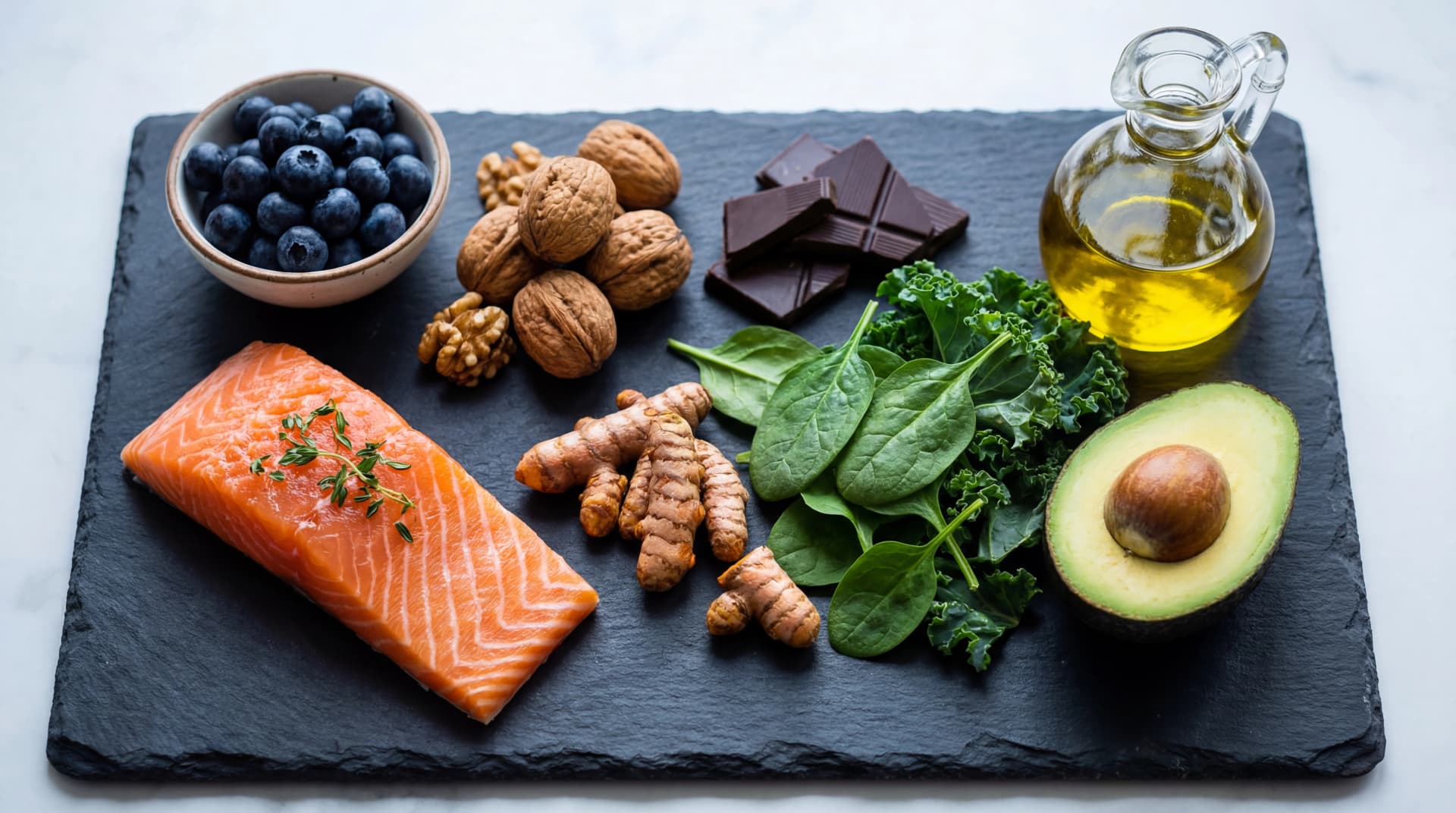 Overhead arrangement of brain-boosting foods including salmon, blueberries, walnuts, and leafy greens on dark slate